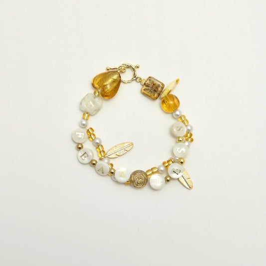 Golden bracelet with “FEARLESS” letter beads and pearl details, top view