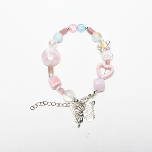 Top view of ME-butterfly bracelet with soft pink tones and “ME” alphabet beads