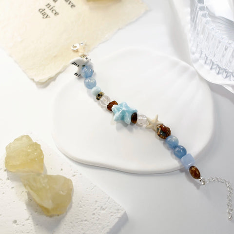 Styled bracelet laid on white ceramic plate, highlighting marine elements