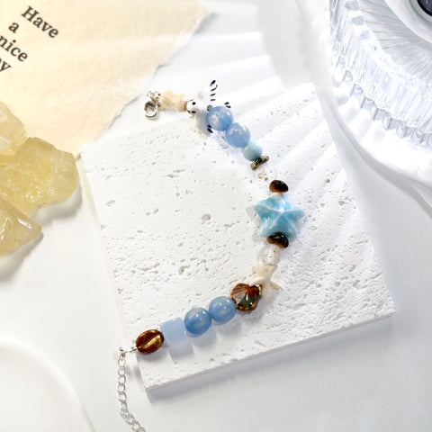 Bracelet on textured white tile, featuring starfish and sea-blue beads