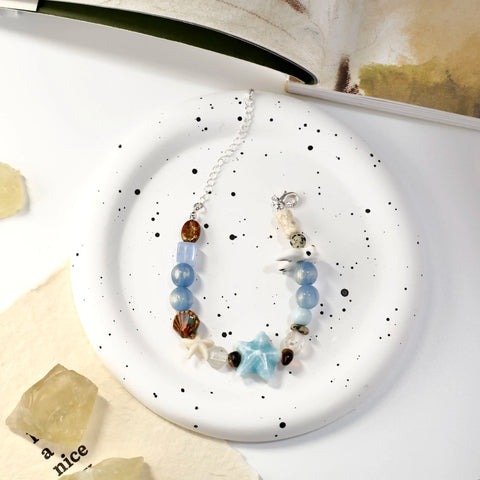Bracelet displayed on black-spotted ceramic plate, ocean motifs highlighted