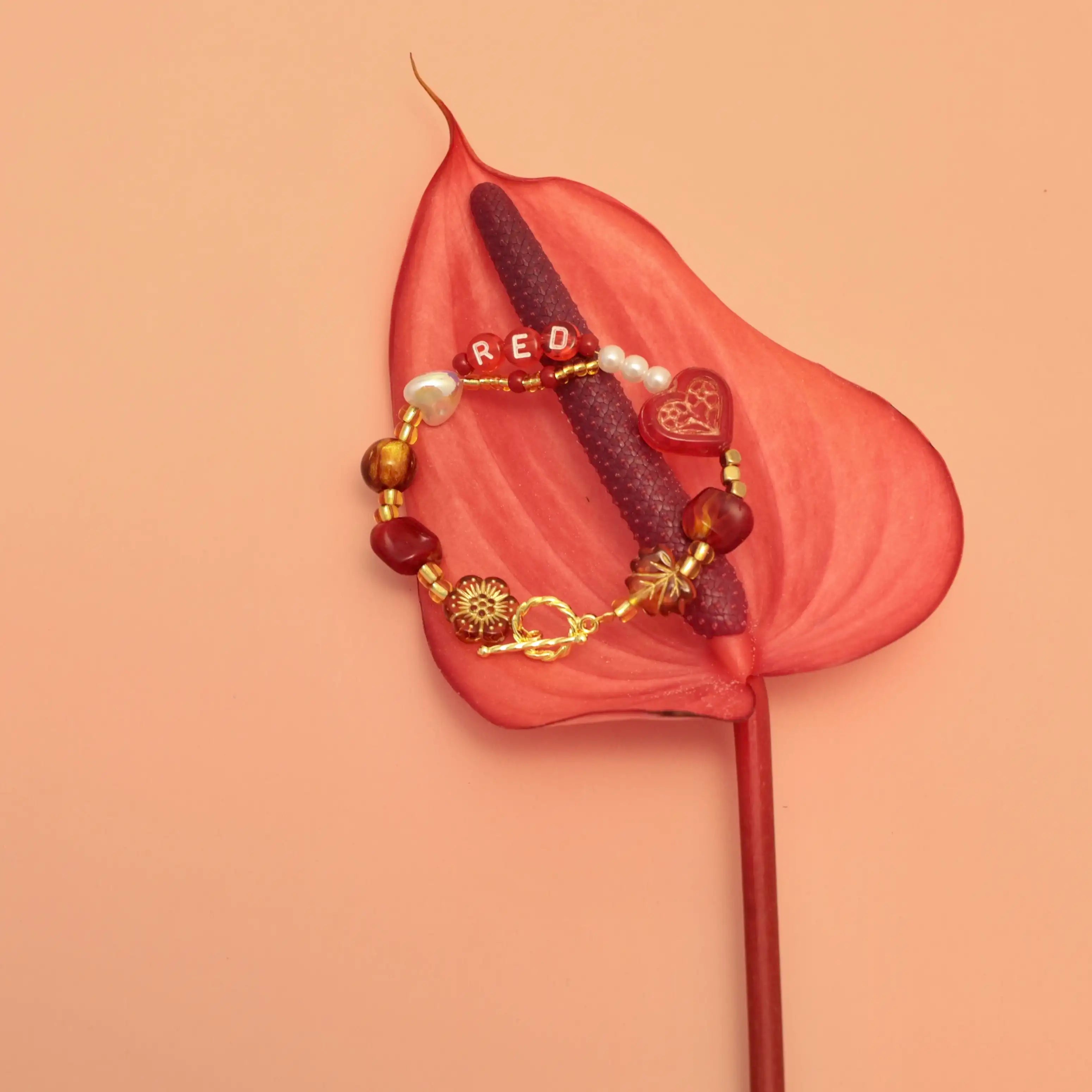 Styled bracelet resting on red flower, emotional aesthetic