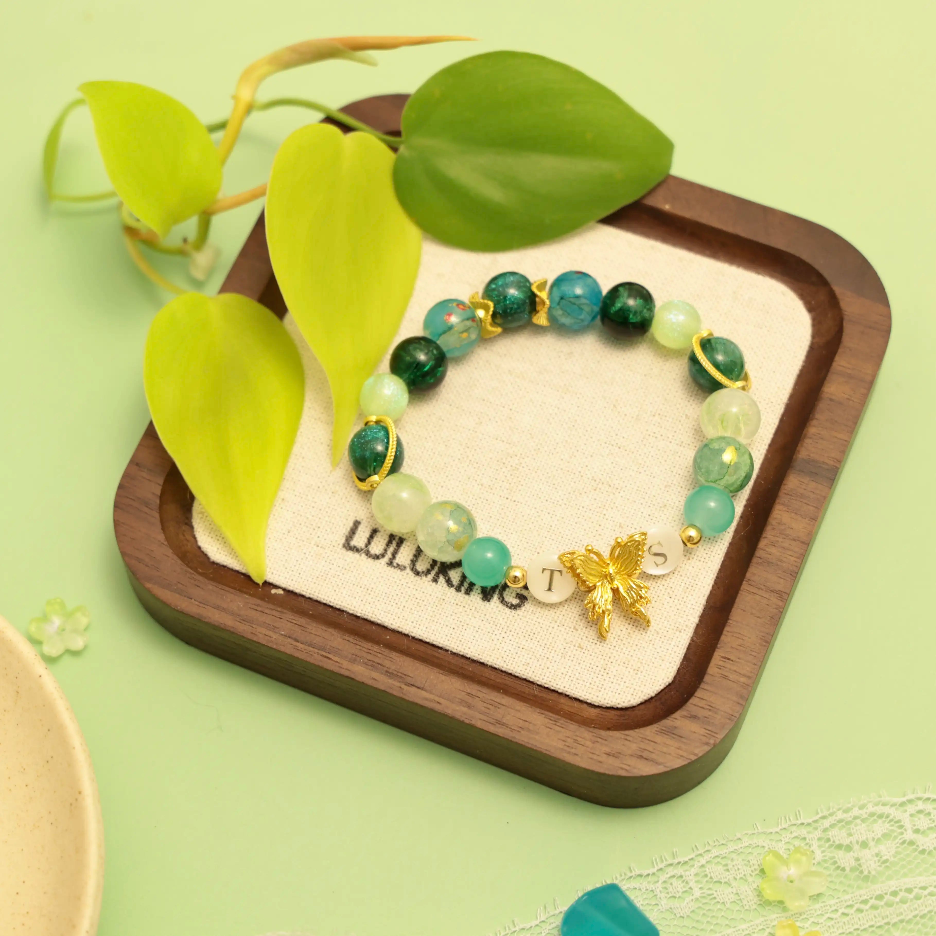 TS bracelet placed in wood jewelry box with green leaves and branding