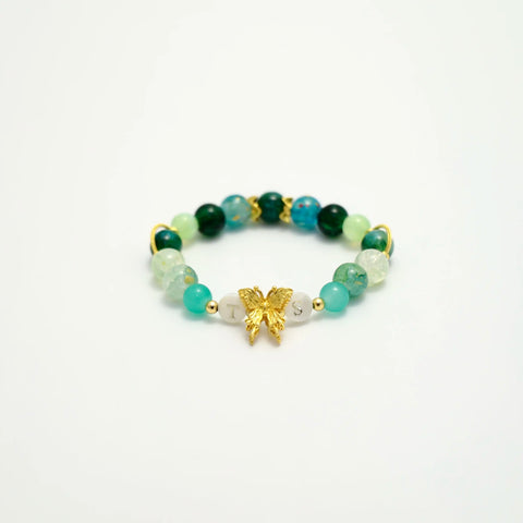 Close-up of bracelet with emerald tones and golden butterfly charm