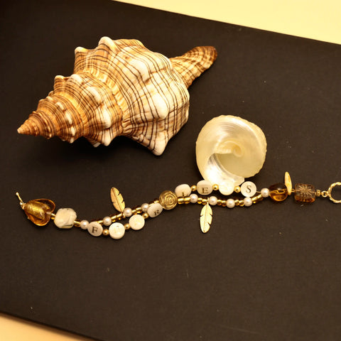 Flatlay of golden FEARLESS bracelet with seashells and soft light accents