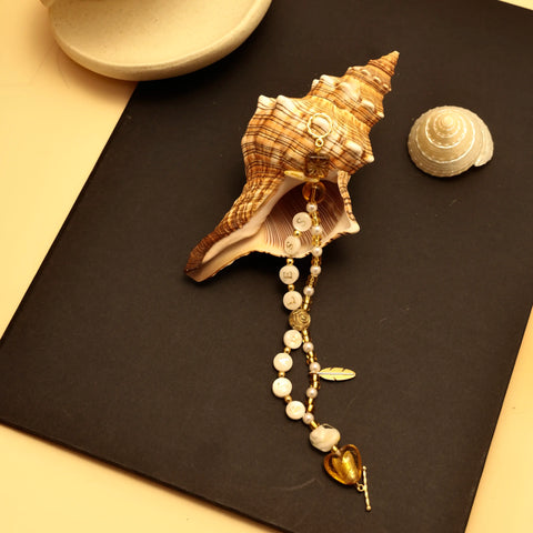 Bracelet hanging from inside shell, showcasing heart and feather elements