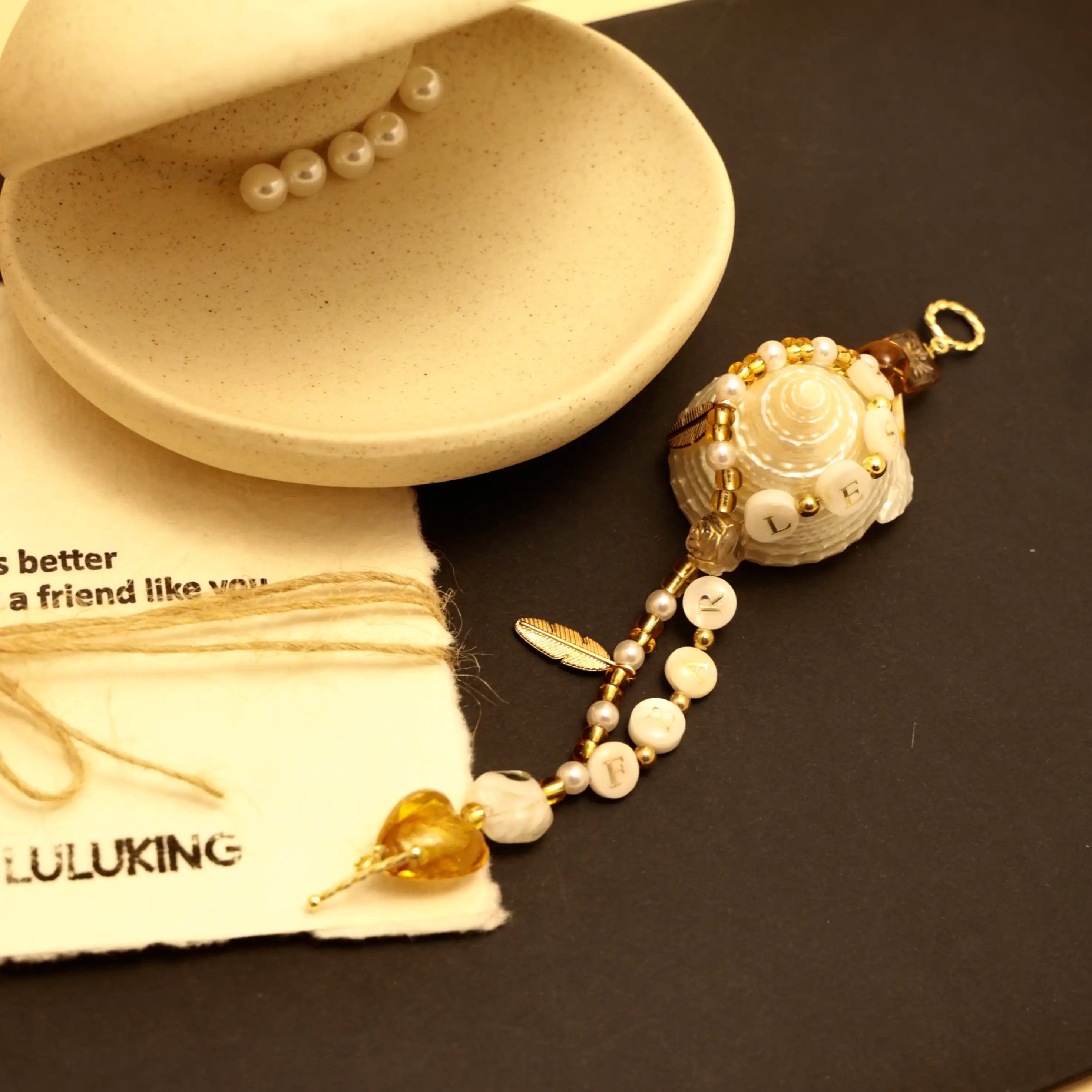 Golden bracelet wrapped around a seashell with pearl details and heart charm