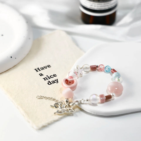 Styled scene with ME-butterfly bracelet beside soft fabric and inspirational card