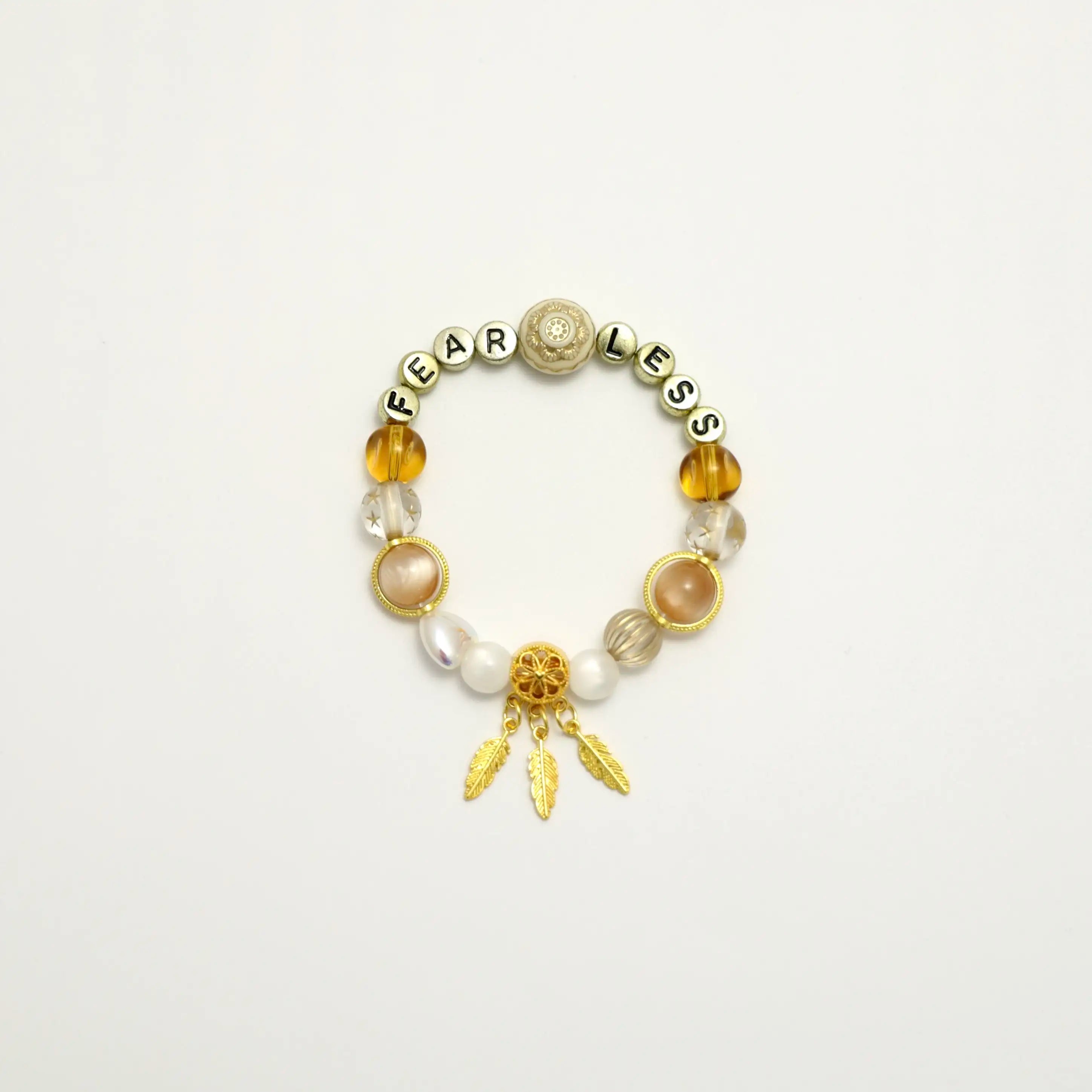 Front view of the Starlit Steps bracelet with FEARLESS letter beads and golden feather charm