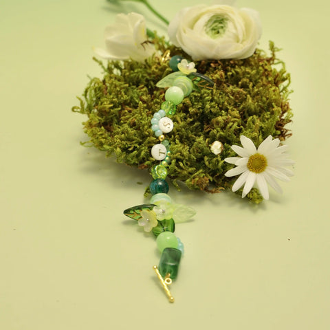 TS bracelet placed on moss with wild daisies, representing natural roots