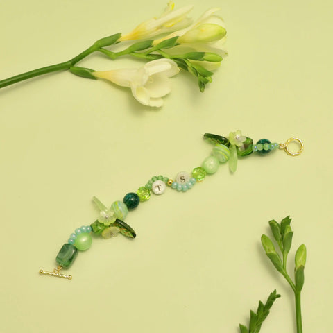 Bracelet styled on green background with white freesias and soft lighting