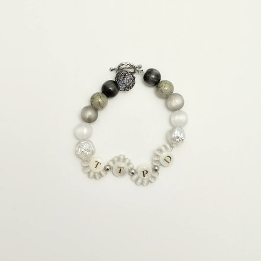 Front view of Tortured Light bracelet featuring TTPD letter beads and silver rose charm