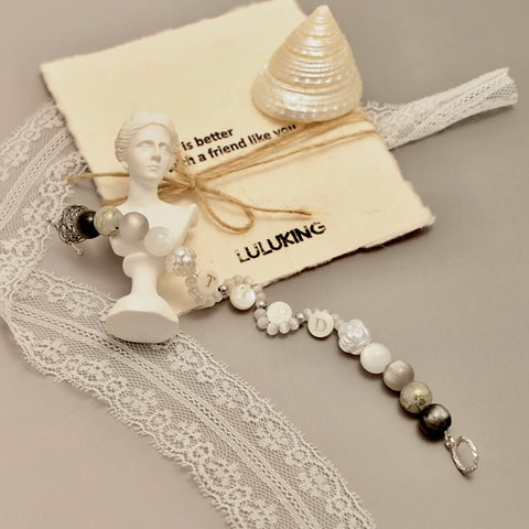 Tortured Light bracelet styled with a miniature bust and vintage paper, evoking timeless pain