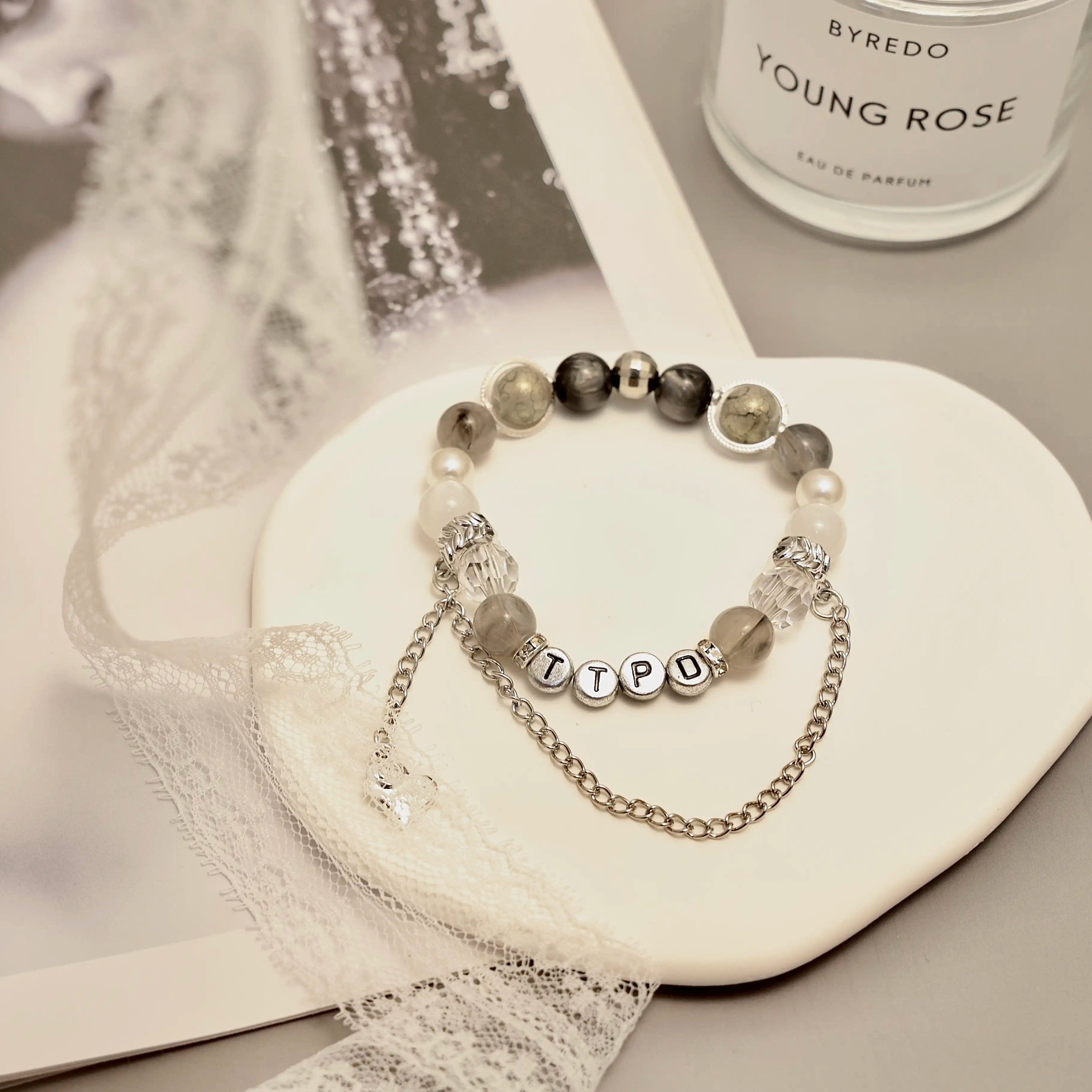 TTPD bracelet close-up on ceramic dish with lace and grayscale tones