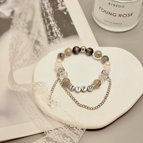 TTPD bracelet close-up on ceramic dish with lace and grayscale tones