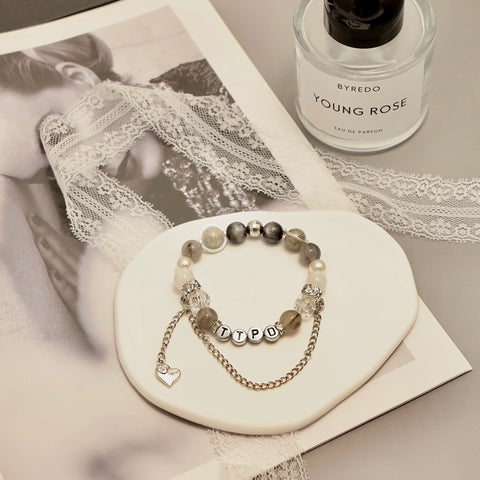 Editorial-style photo with TTPD bracelet, Young Rose perfume and lace