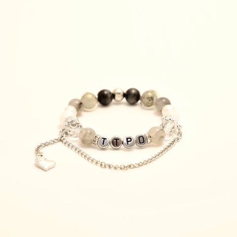 Flat-lay of grayscale TTPD bracelet with chain and heart accent